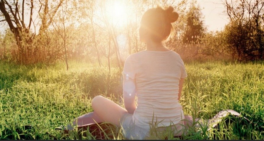 Imagen de persona sentada en el césped, tomando el sol, como mecanismo de obtención de Vitamina D
